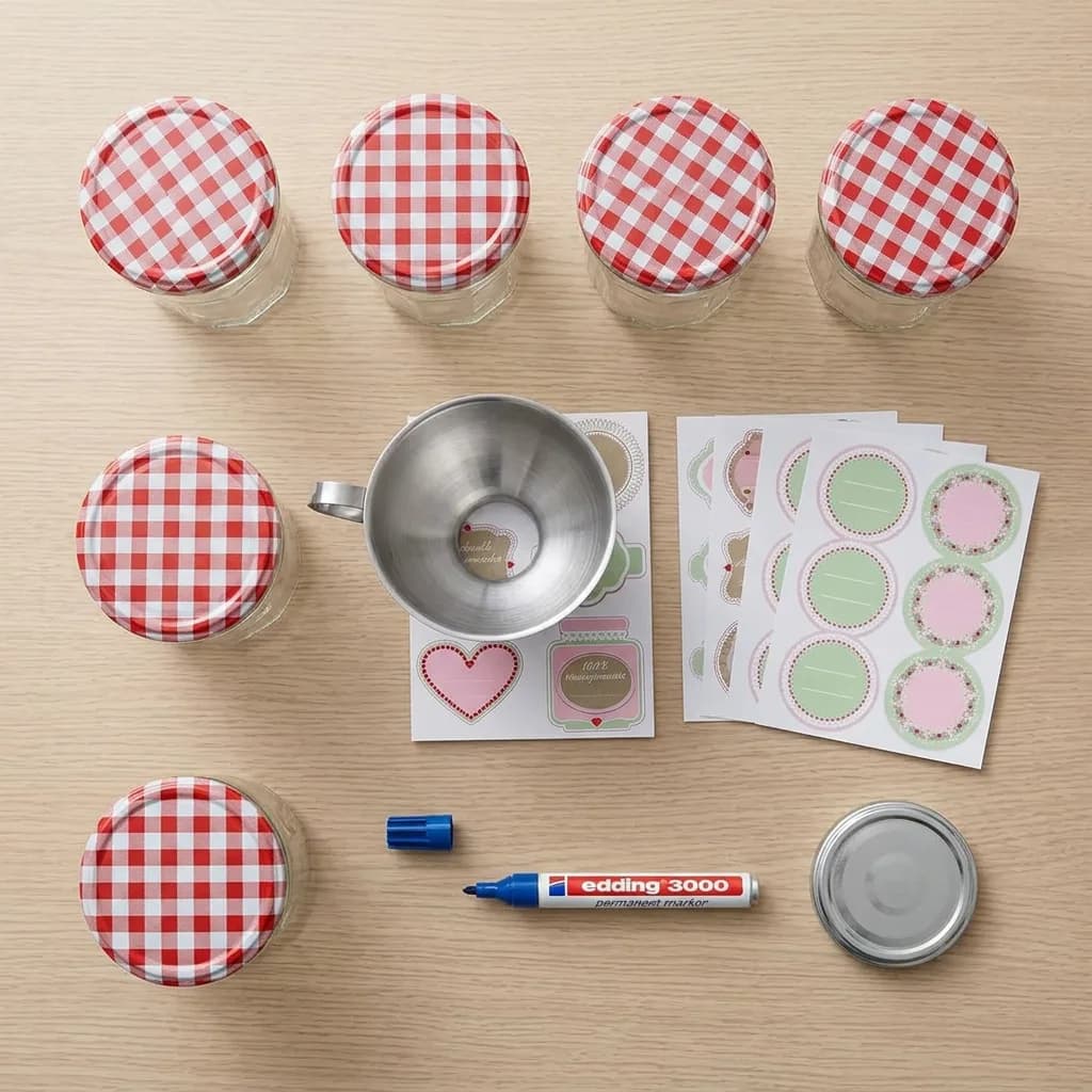 Einmachen und Einkochen: 6 Einmachgläser mit rot-weiss karierten Twist-off-Deckeln, Metalltrichter, Etiketten-Bögen, blauer Permanent-Marker und einzelner Deck…